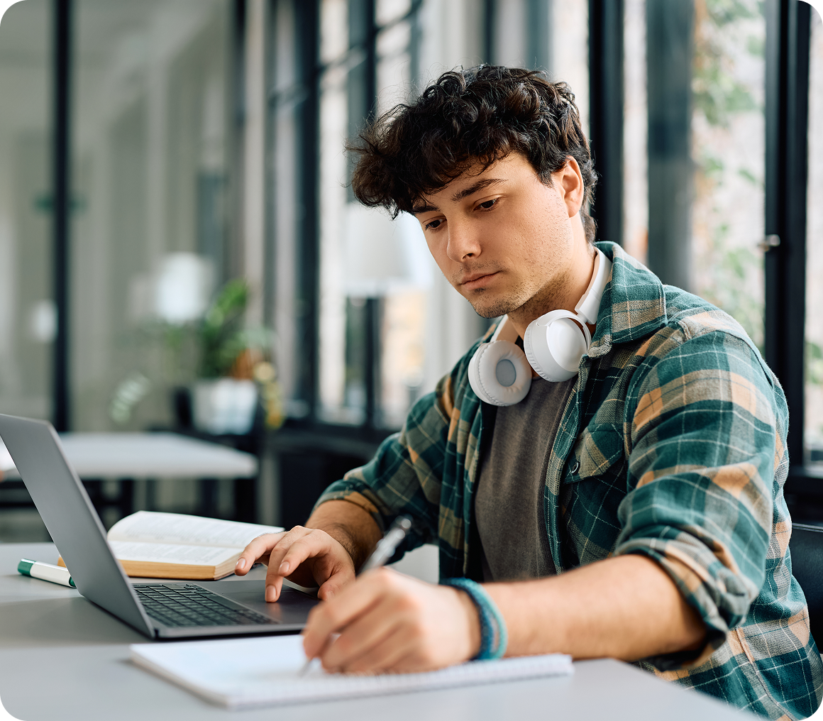 Young man studying with laptop and headphones.