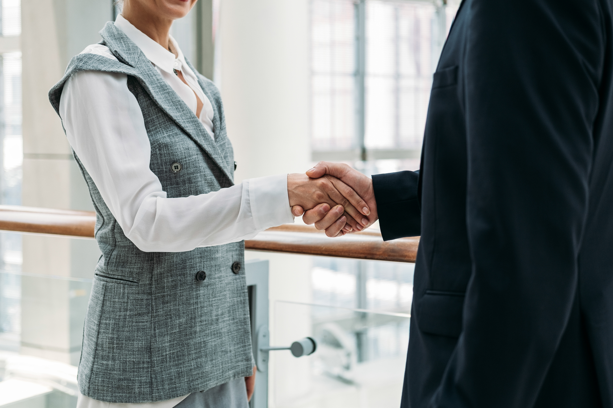 Two professionals shaking hands in a bright office setting.