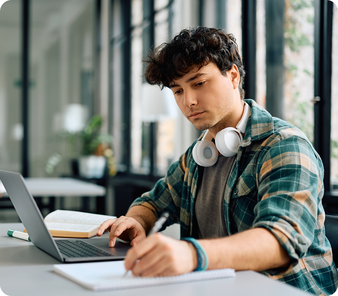 Young man studying with laptop and headphones.