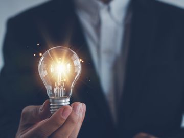Hand holding a glowing light bulb symbolizing innovation.