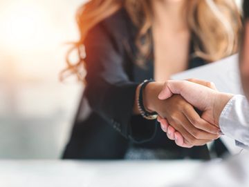 Two people shaking hands, symbolizing agreement or partnership.