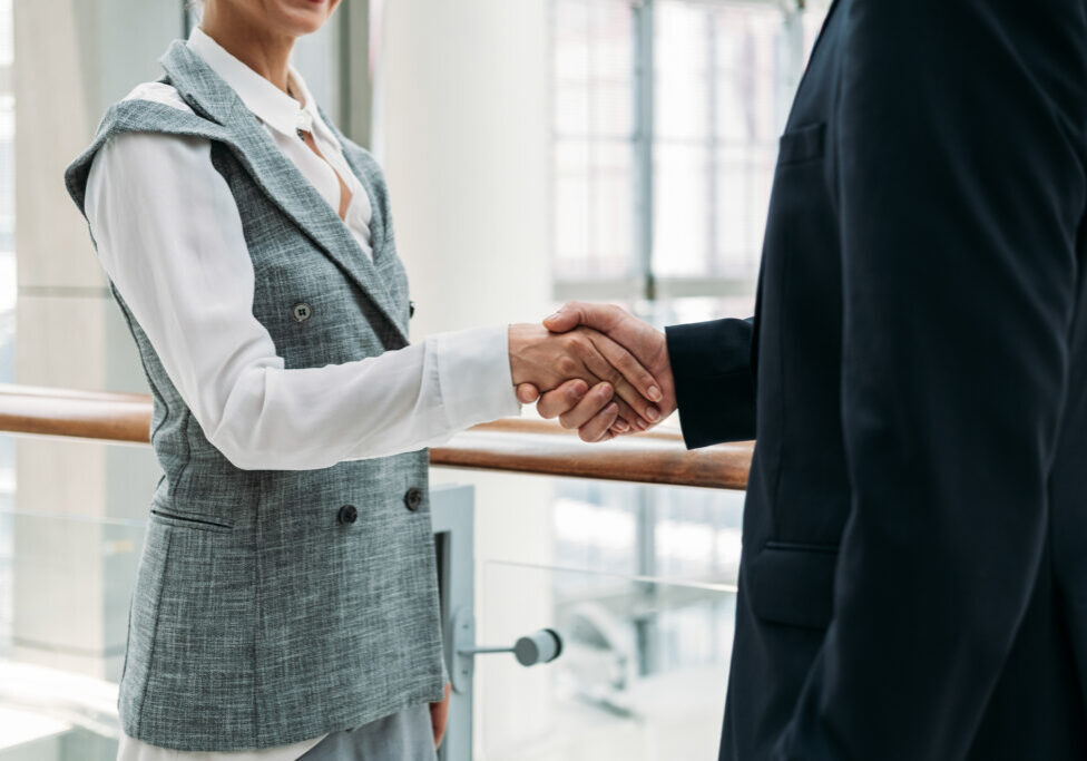 Two professionals shaking hands in a bright office setting.